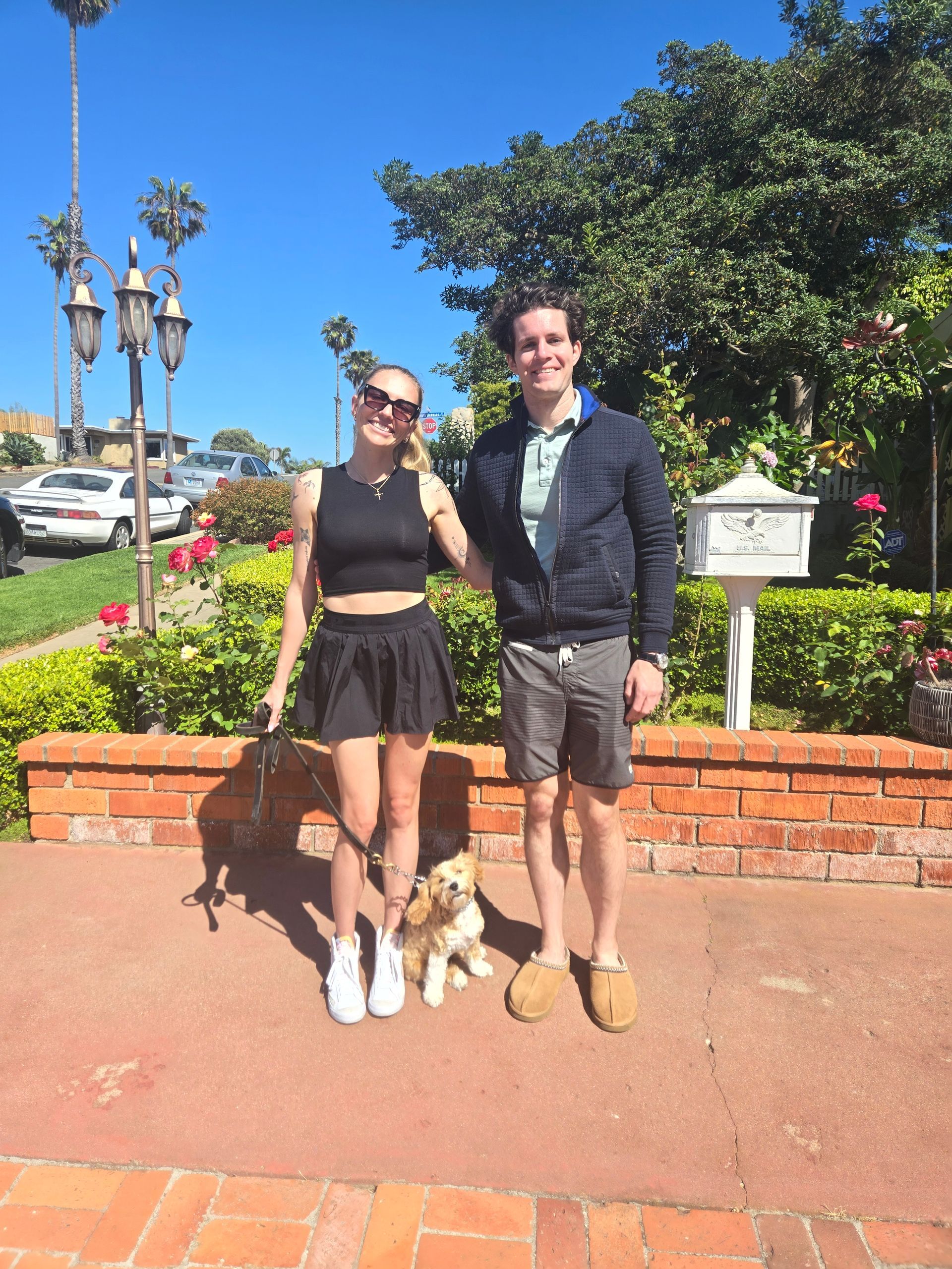 A man and a woman are standing next to a small dog.