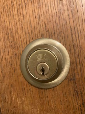 Close-up of a brass deadbolt lock on a wooden door.