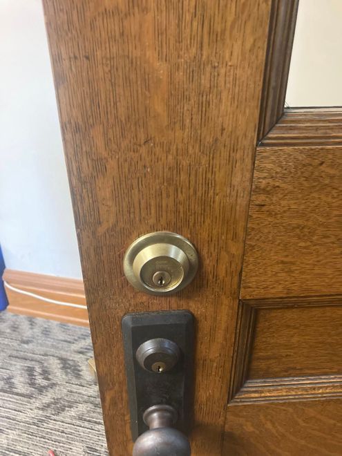 Close-up of a wooden door with a brass deadbolt and dark handle latch.