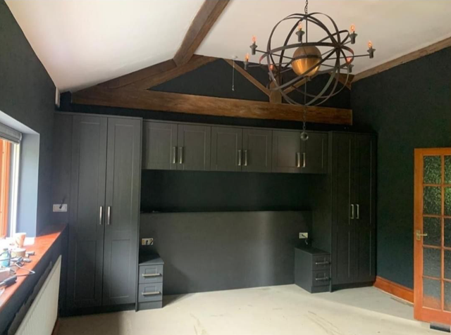Empty room with dark built-in cabinets, vaulted ceiling, and a large chandelier.