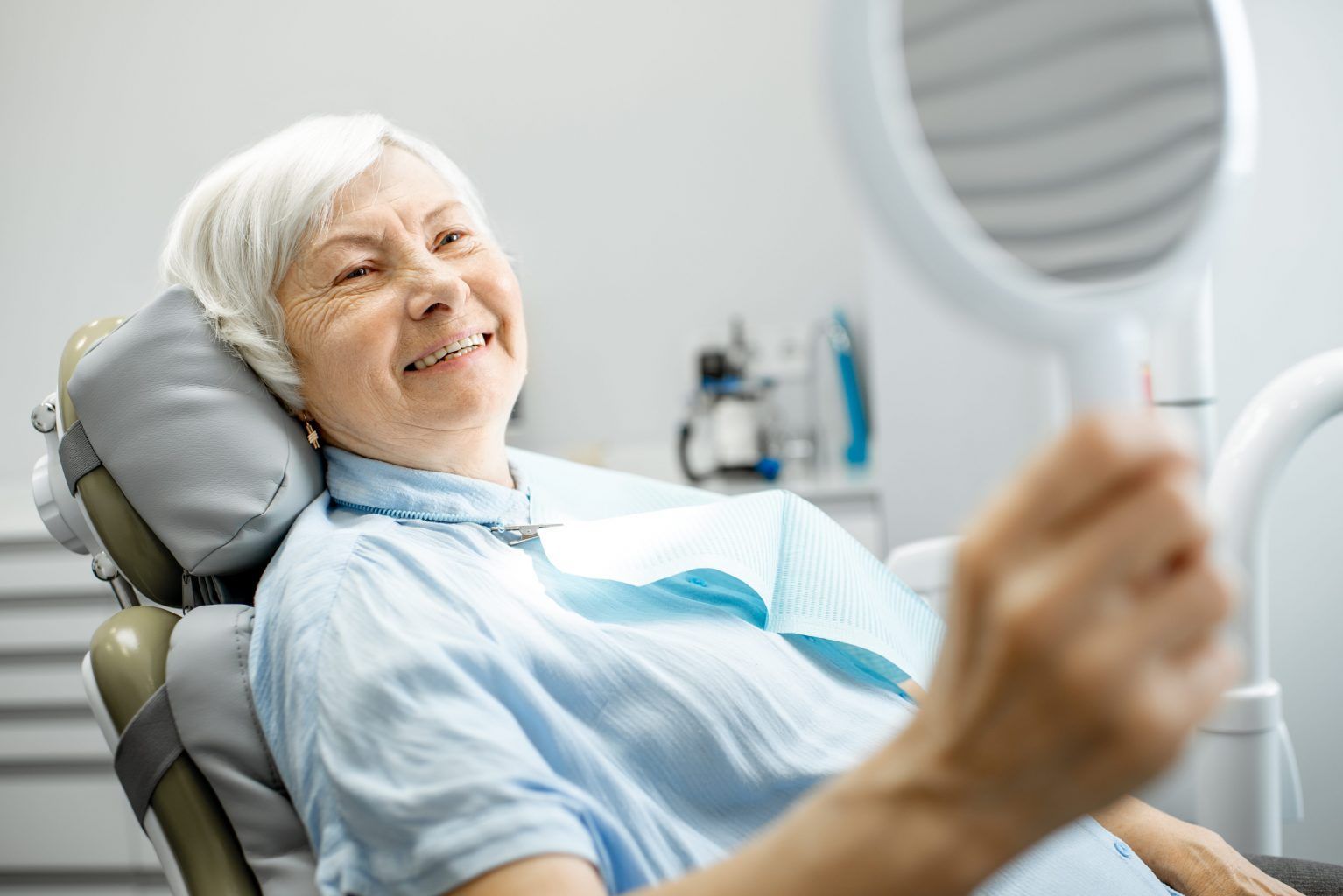 old woman looking at her teeth on a mirror
