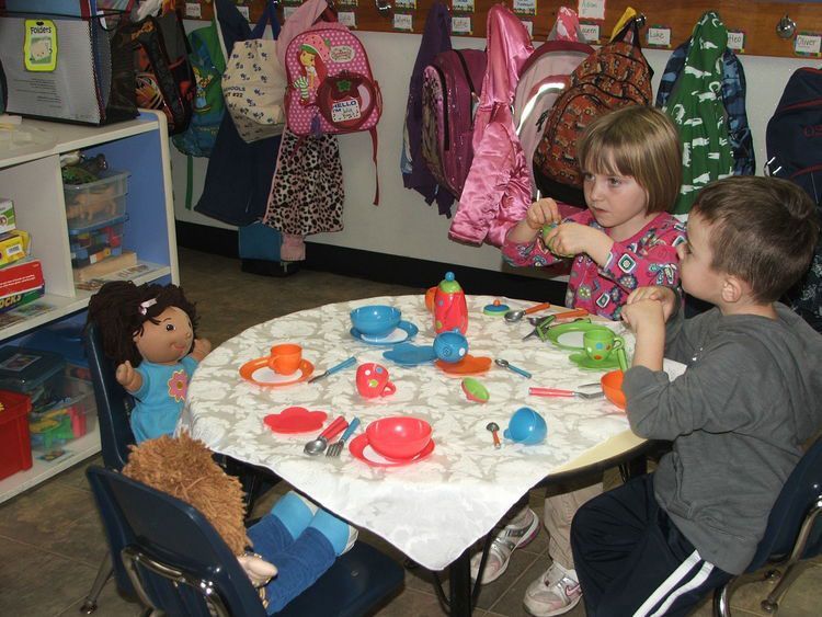 A boy and a girl are playing with toys at a table