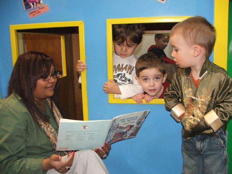 A woman is reading a book to two young boys