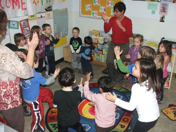 A group of children are dancing in a room with a sign that says come