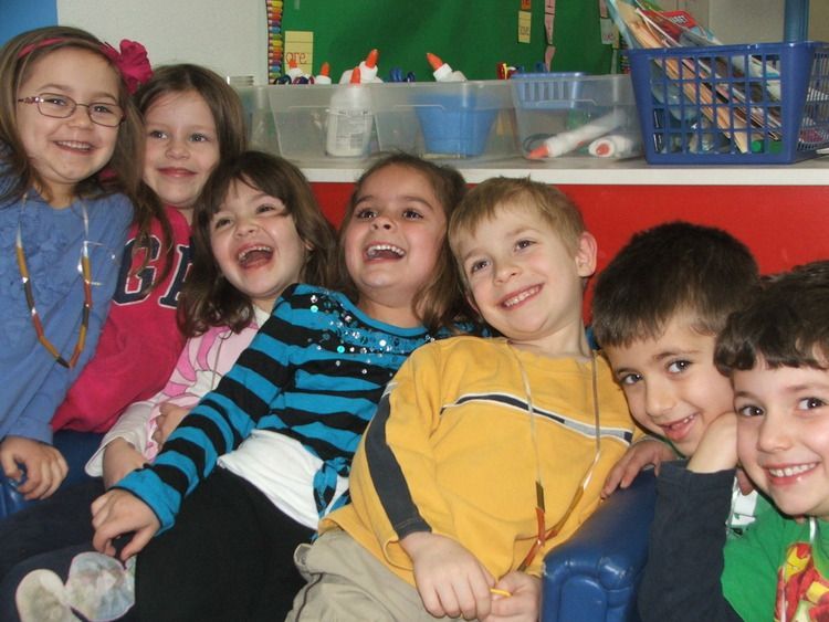 A group of children are posing for a picture with one girl wearing a shirt with the letter b on it