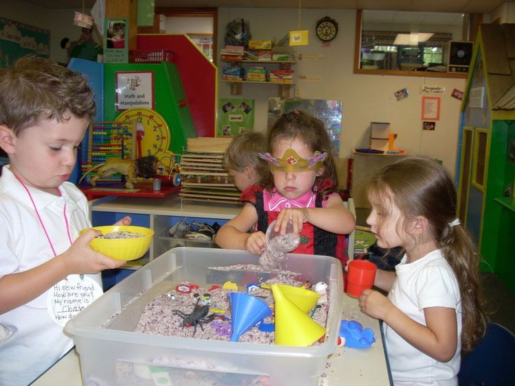 A group of children are playing with sand in a classroom