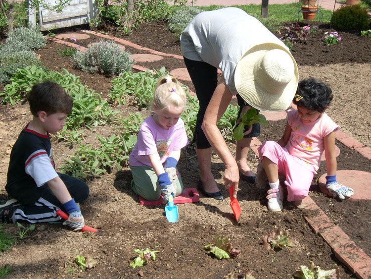 A woman and three children are working in a garden