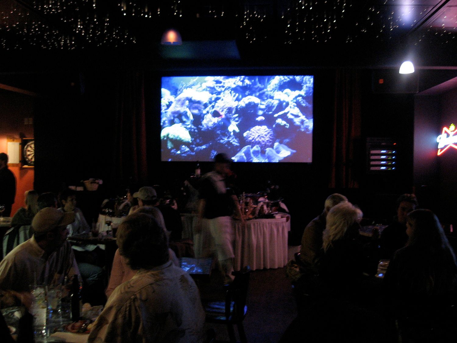 A group of people sitting in front of a large screen in a dark room