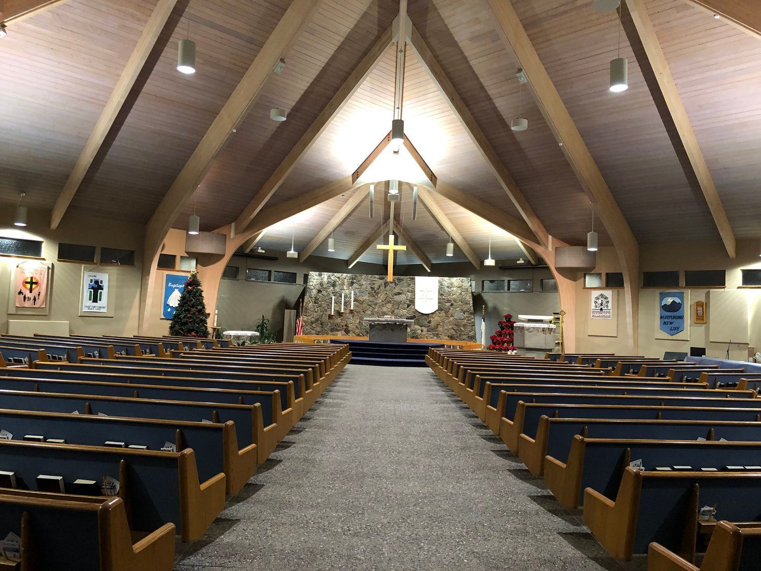 The inside of a church with rows of benches and a cross hanging from the ceiling