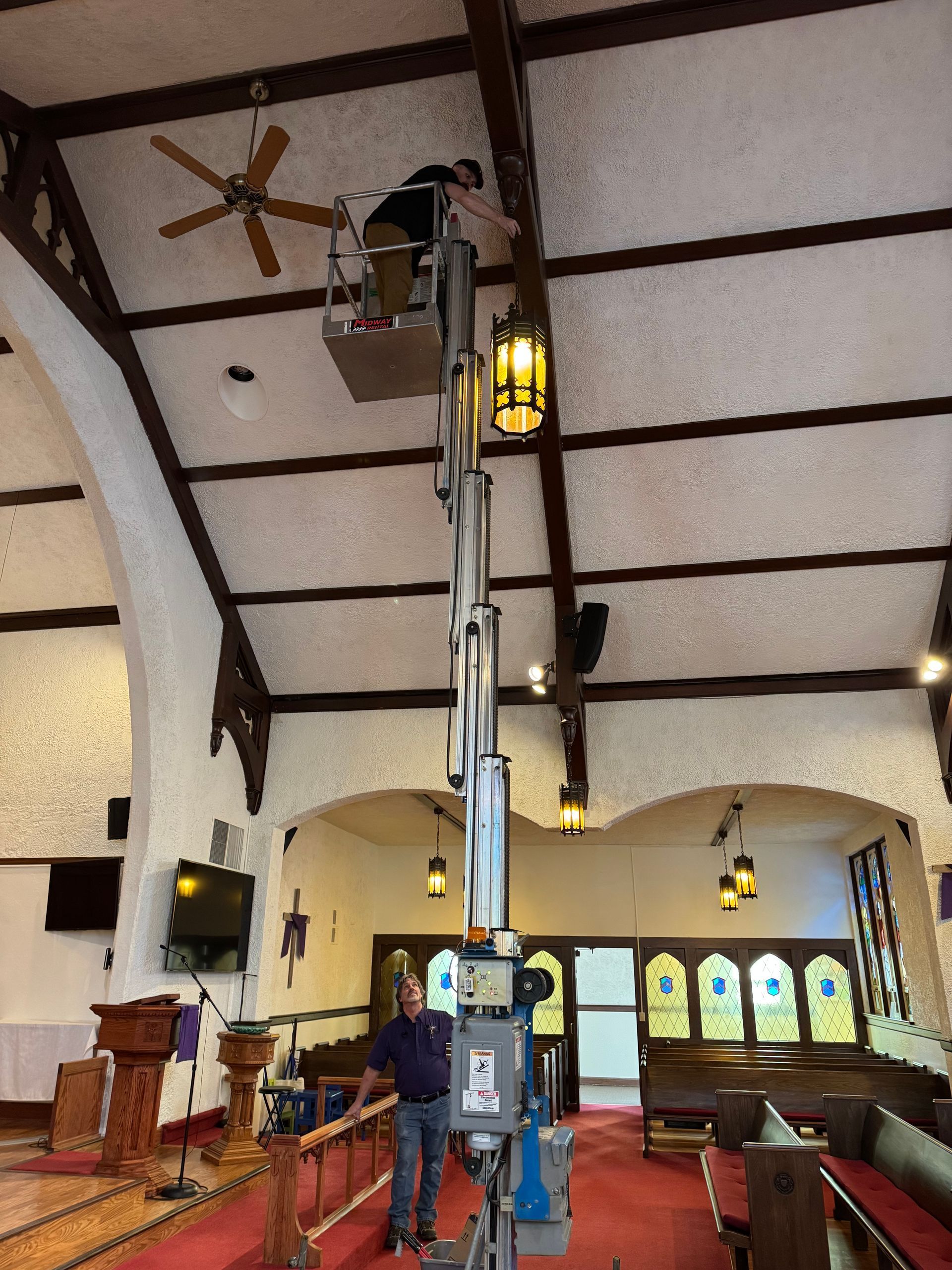 A man is standing on a lift in a church.