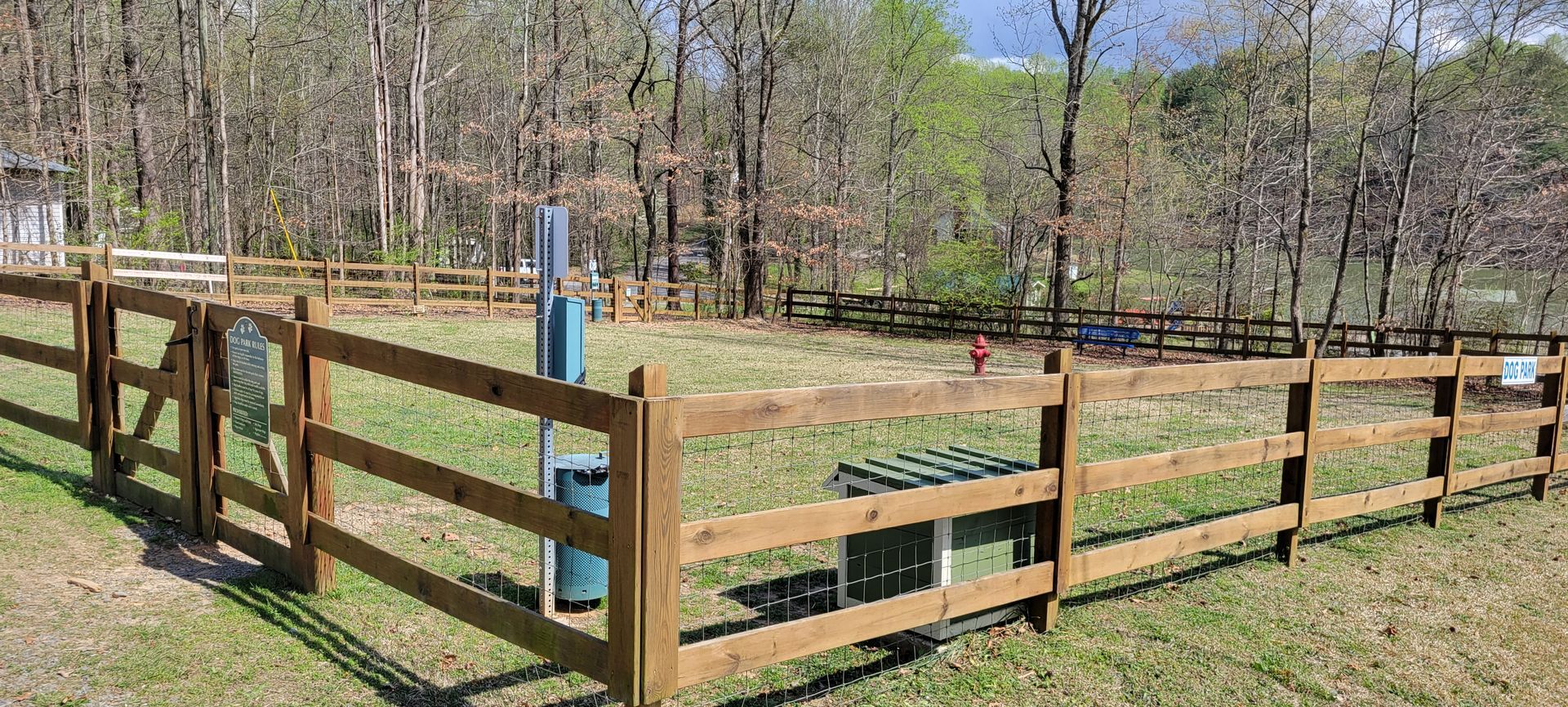 A wooden fence surrounds a field with trees in the background