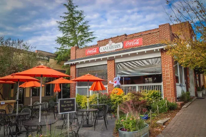 A restaurant with orange umbrellas and tables outside