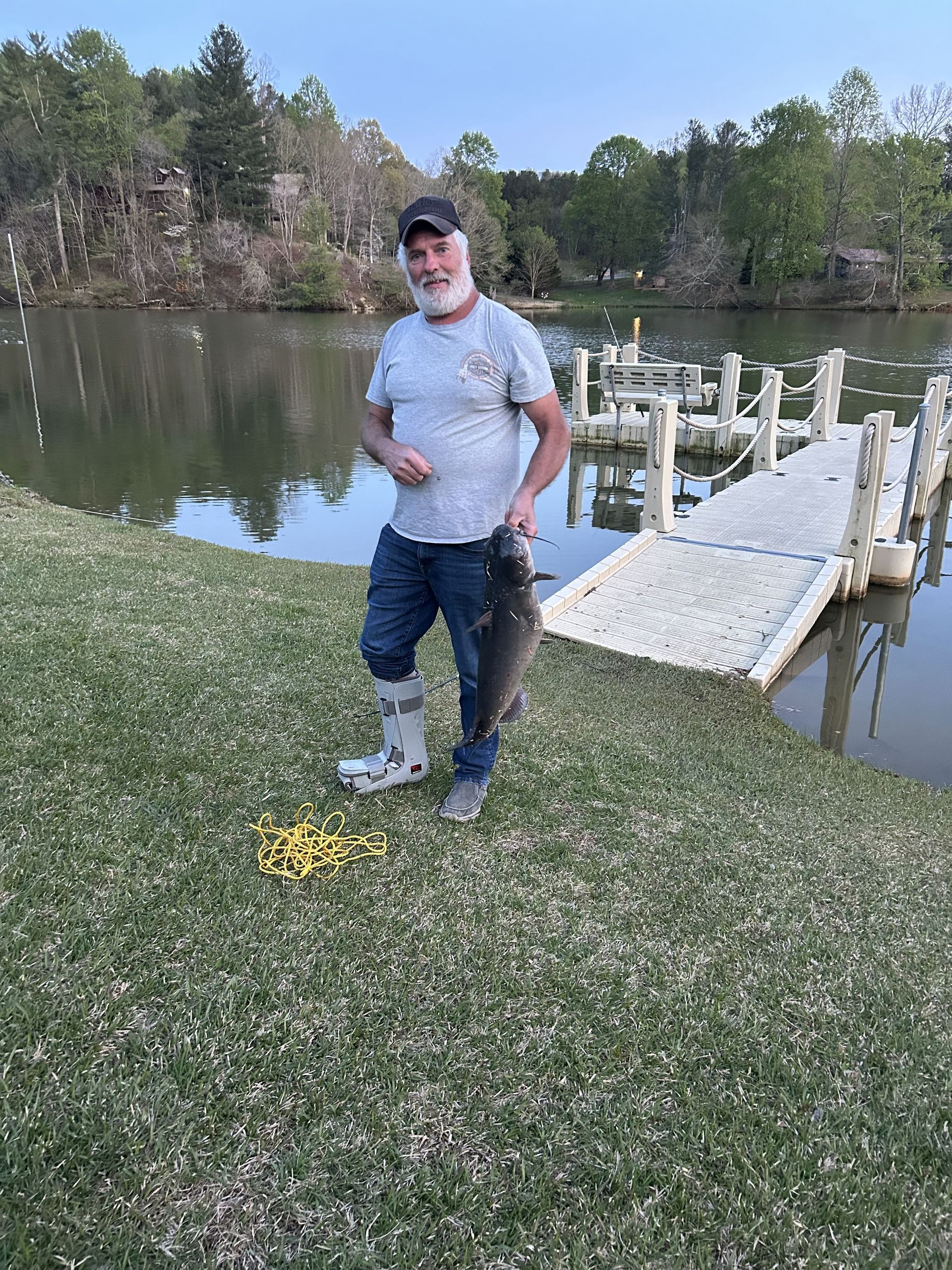 A man is holding a large fish in front of a lake.