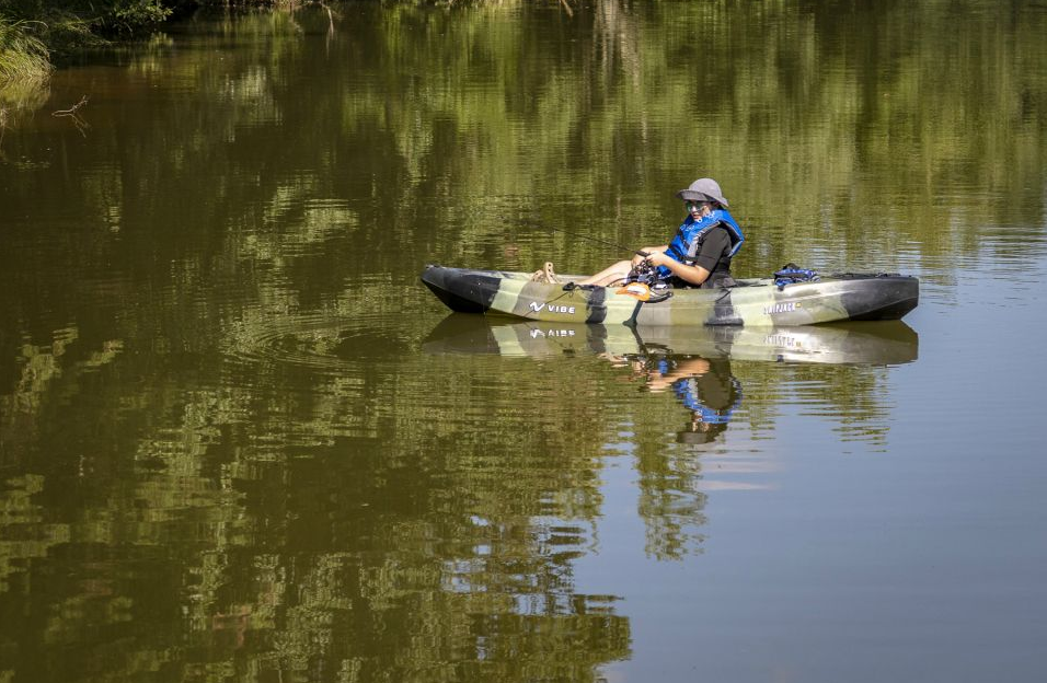 A man is sitting in a kayak on a lake