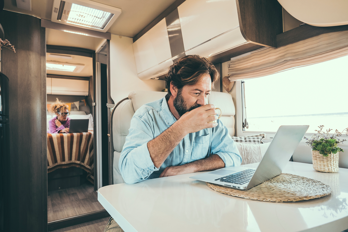 A man is drinking coffee while using a laptop