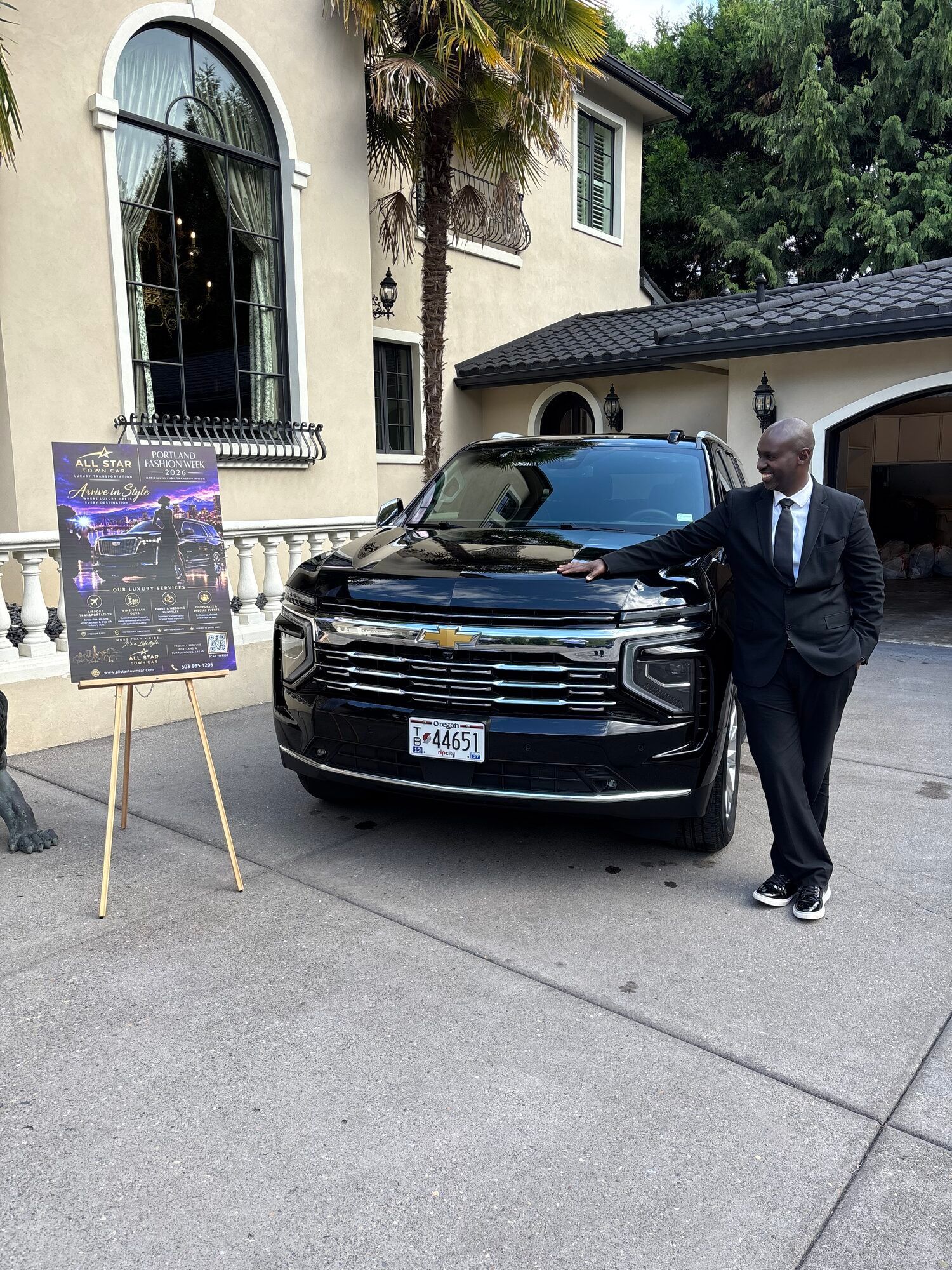 Chauffeur beside a black Chevrolet Suburban at Portland Fashion Week, booked through our executive car service in Oregon and Southwest Washington
