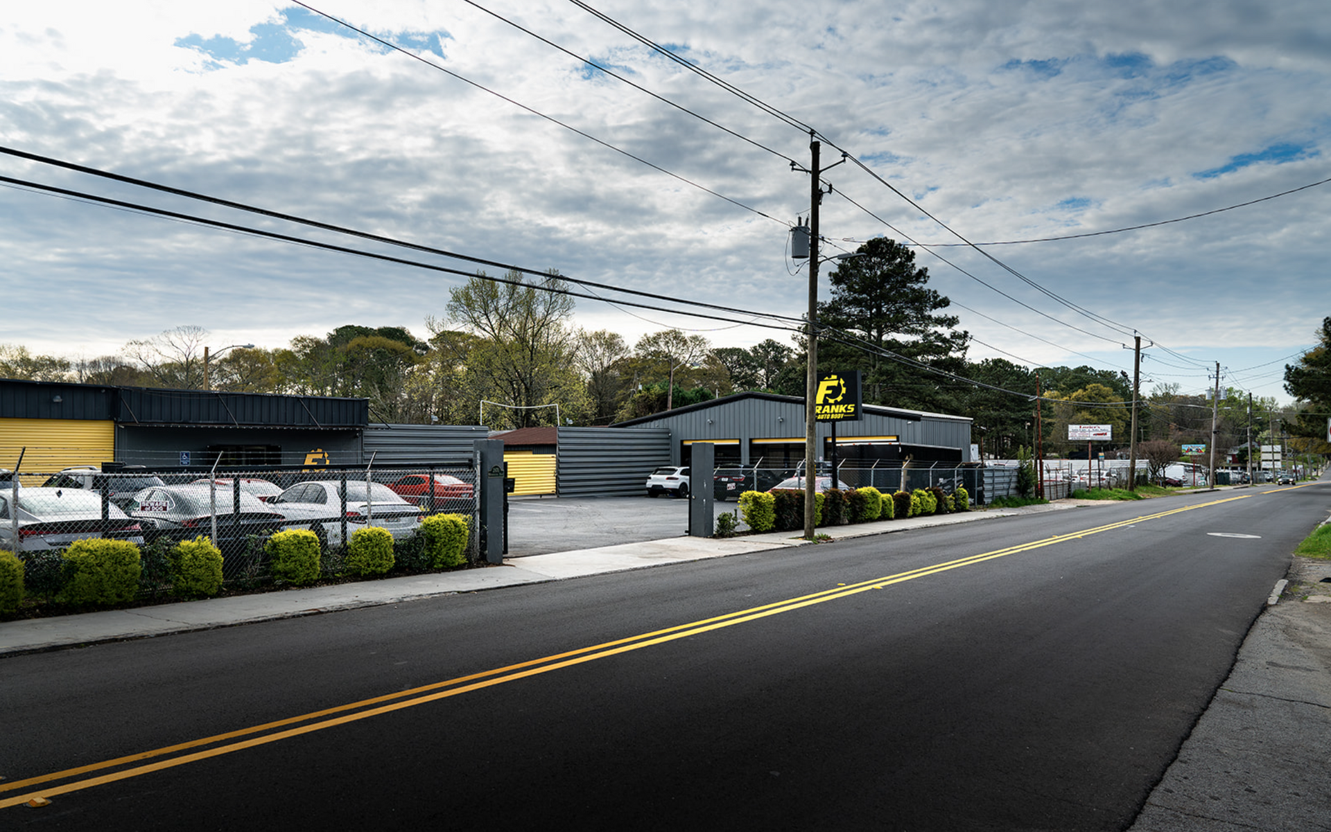 Roadside gas station and convenience store under cloudy sky, with parked cars and power lines