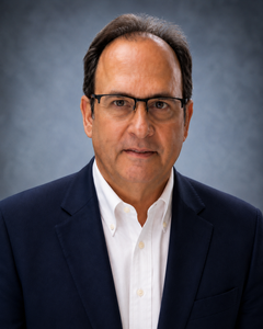 A man in a suit and cowboy hat is smiling for the camera.