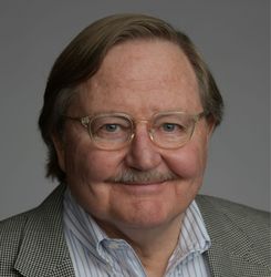 A man in a tuxedo and bow tie is smiling for the camera.