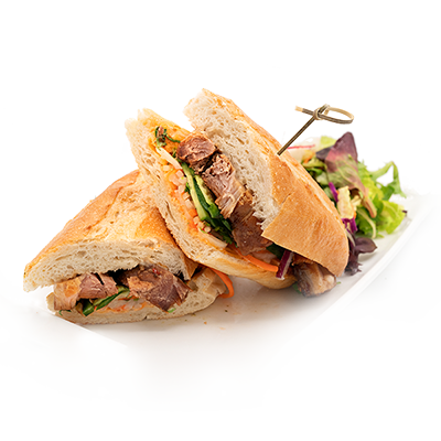 Sandwich halves with beef and greens on a white plate with a small side salad
