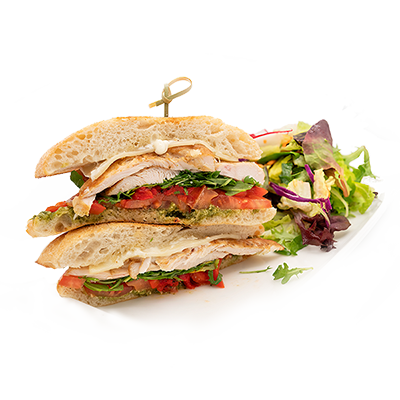 Stacked sandwich with lettuce and tomato, served with mixed greens on a white plate