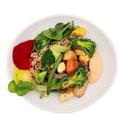 Salad bowl with greens, broccoli, potatoes, beets, and creamy dressing on a white plate