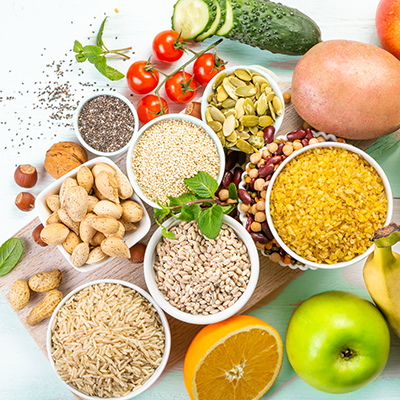 Assorted grains, nuts, fruits, and vegetables arranged on a white surface.