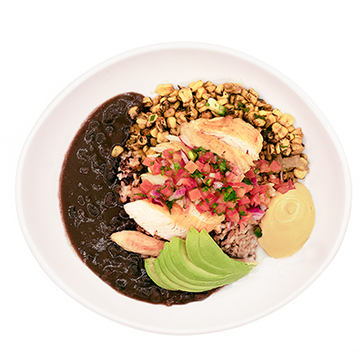 Bowl of rice topped with sliced chicken, avocado, beans, corn, pico de gallo, and lime wedge