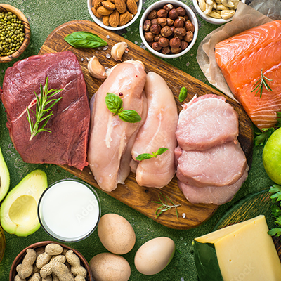 Assorted raw meats, eggs, dairy, nuts, and vegetables arranged on a wooden cutting board.
