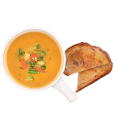 Cup of creamy orange soup with herbs and diced vegetables, served with two slices of toasted bread.
