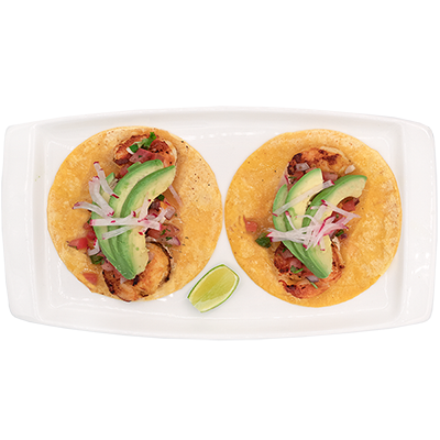 Two tacos with avocado and onions on a white plate, with a lime wedge
