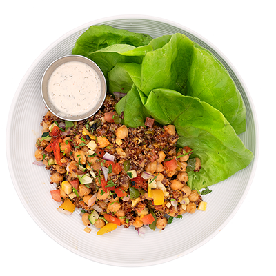 Salad bowl with chickpeas, diced vegetables, green lettuce, and a side of creamy dressing
