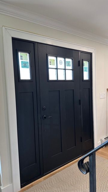 Black front door with small glass panes, viewed inside a home hallway.