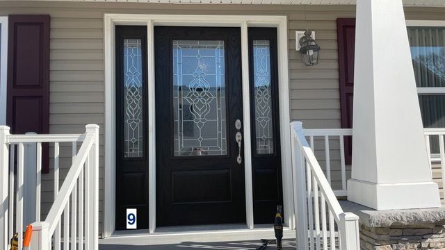 Front porch with black double doors, white railings, and decorative side windows
