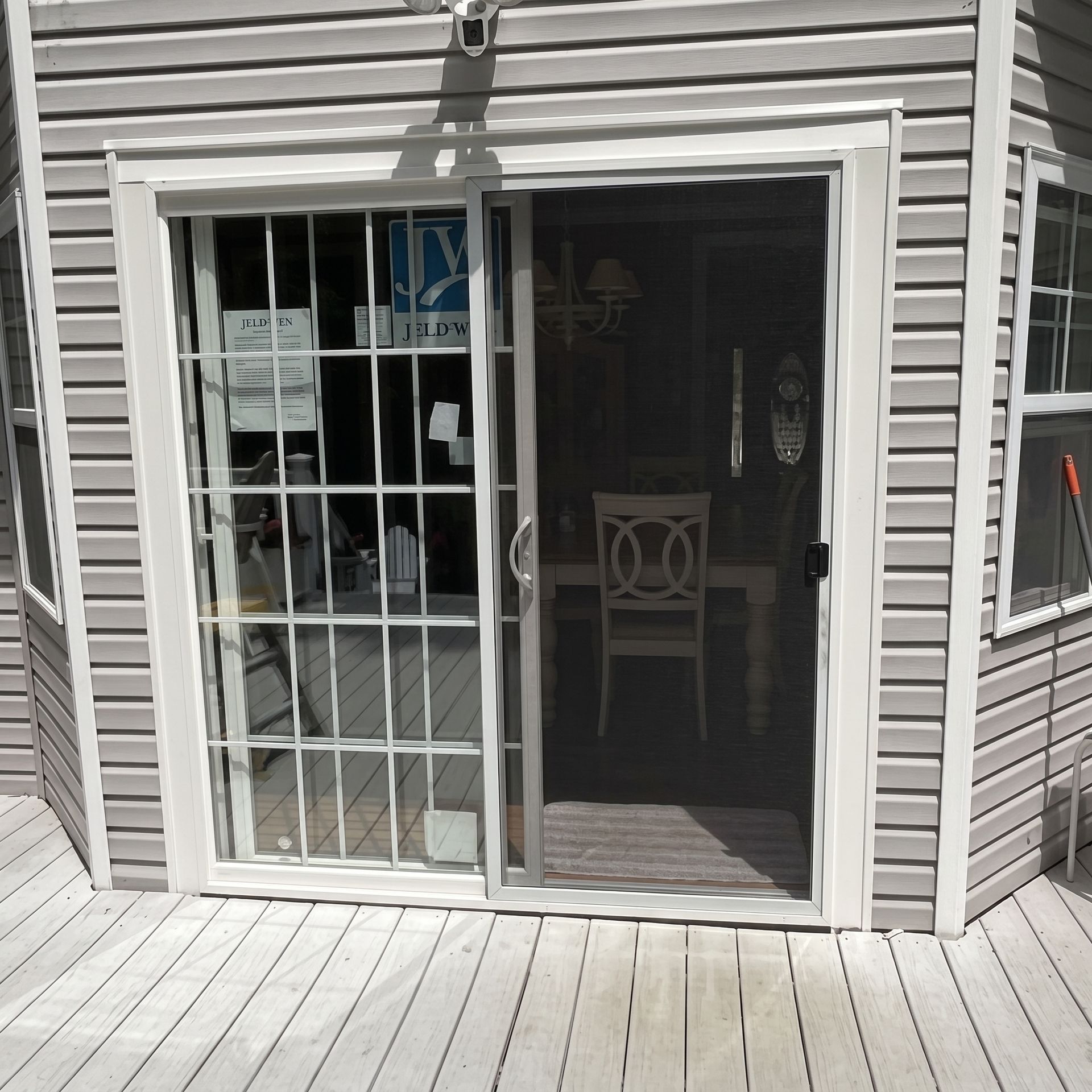 Sliding glass door and adjacent window on a gray house exterior, with a wooden deck in front.