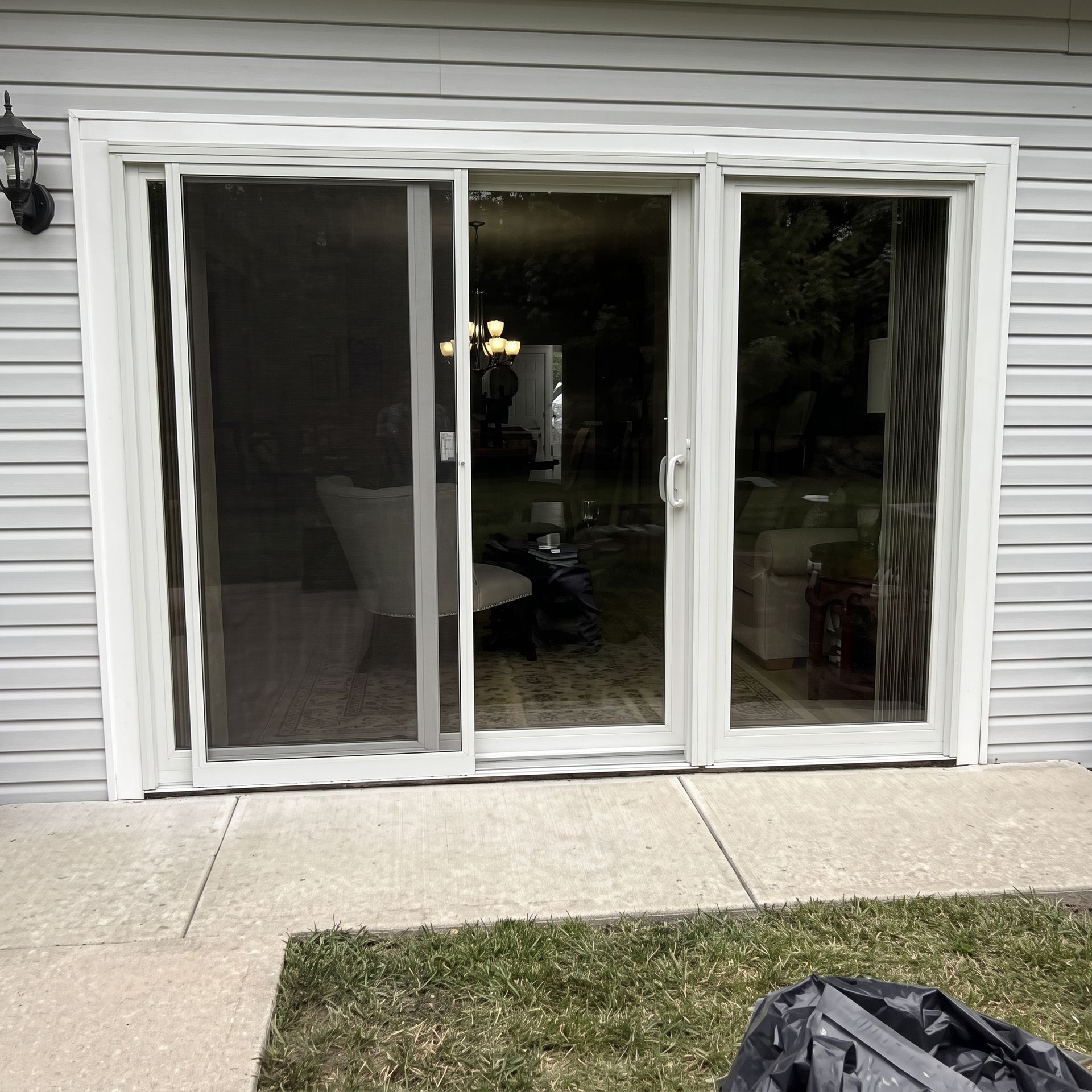 White-framed sliding glass doors on a house exterior with patio and grass in front.
