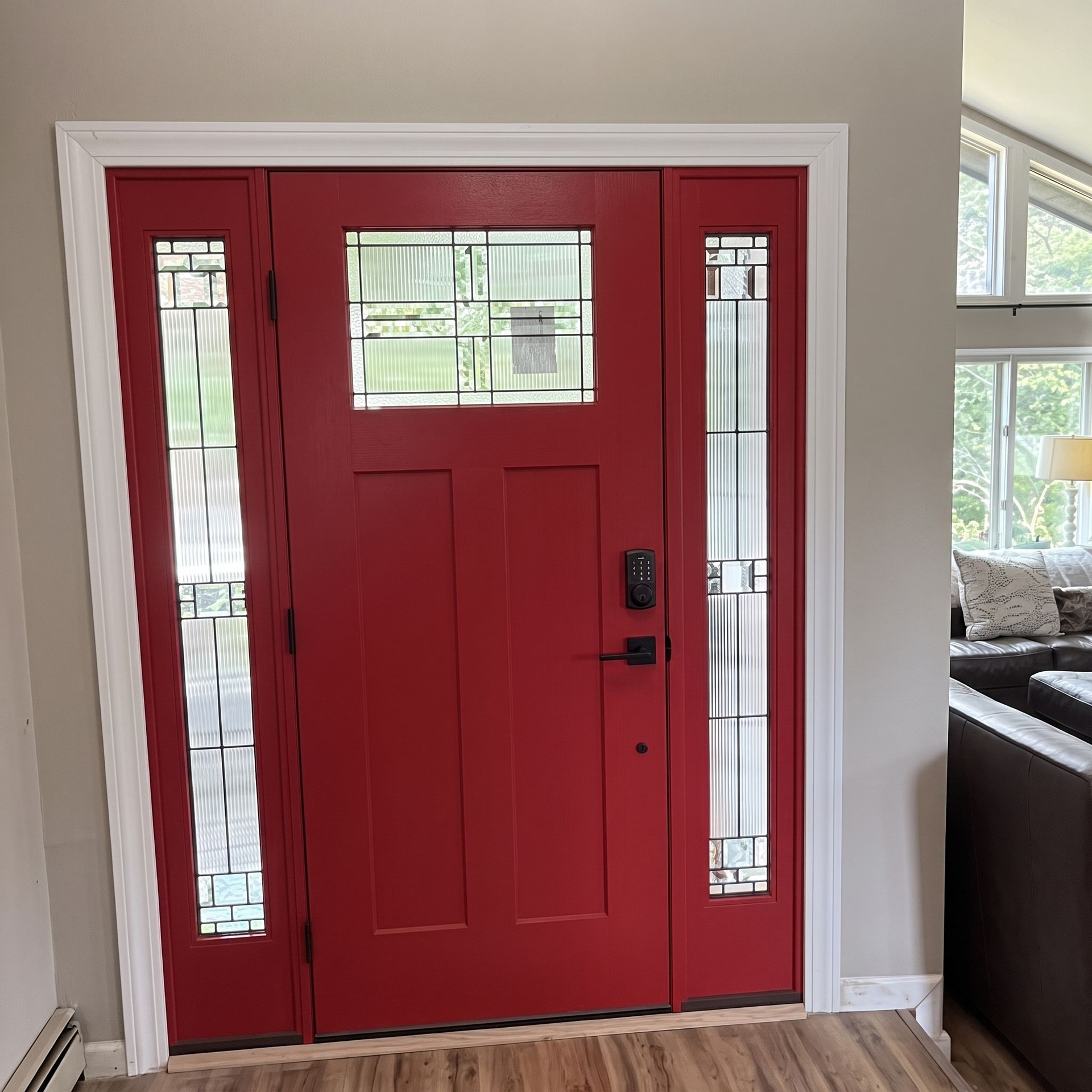 Red front door with glass side panels in a bright home entryway