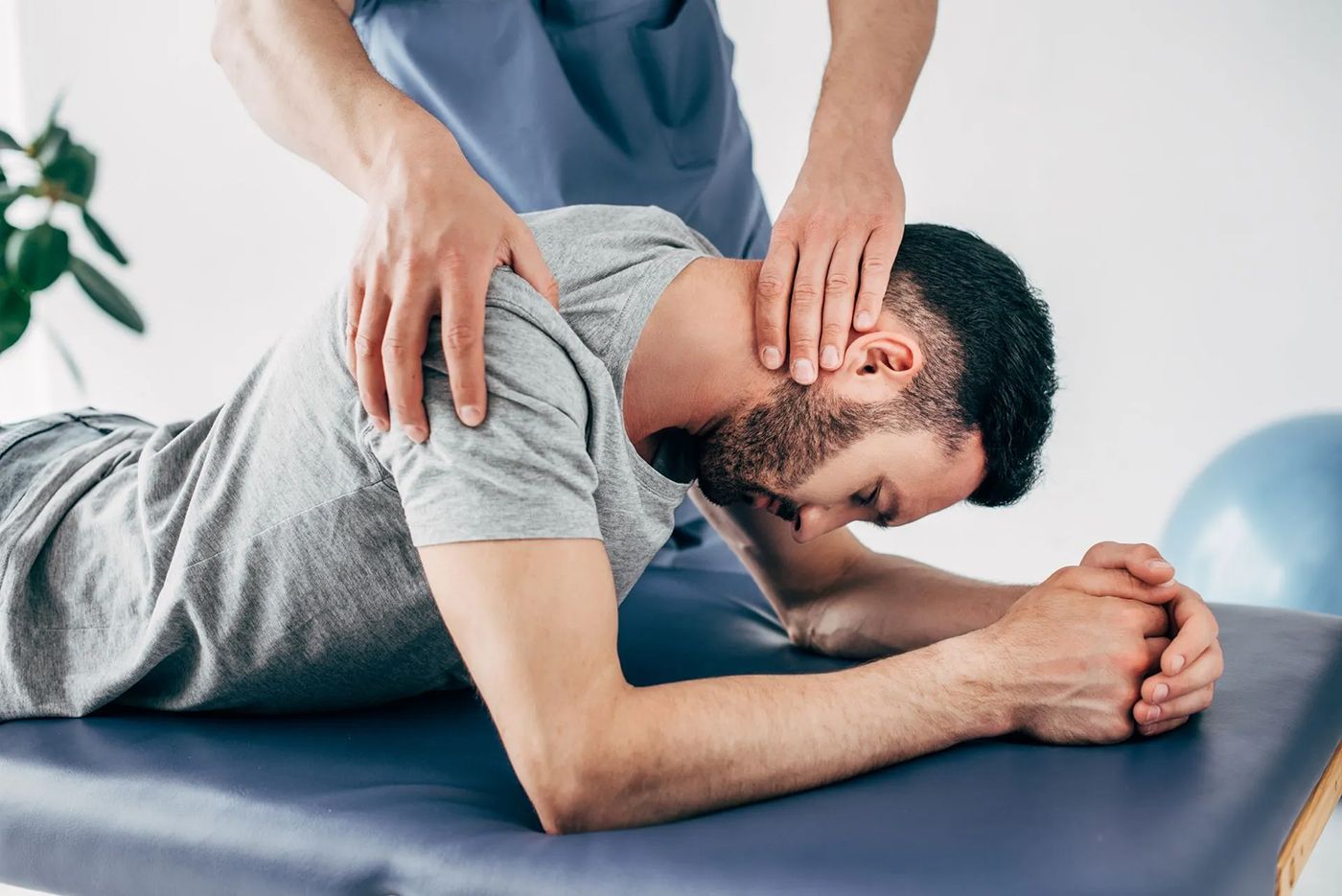 A man is laying on a table getting a massage from a doctor.