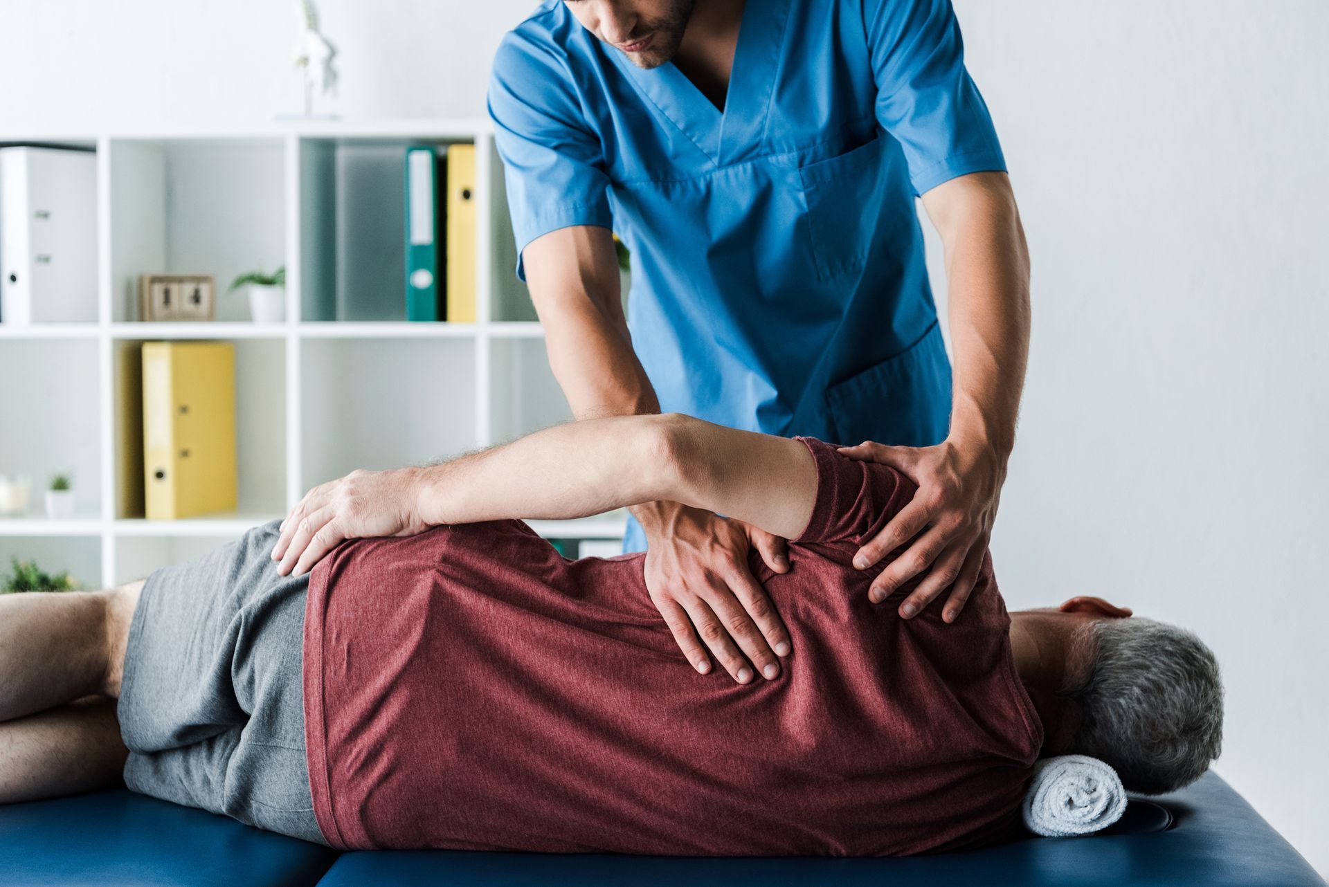 A man is laying on a table getting a massage from a doctor.
