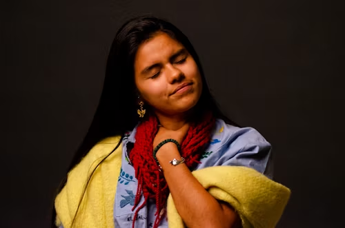 A woman is holding a yellow blanket around her neck.
