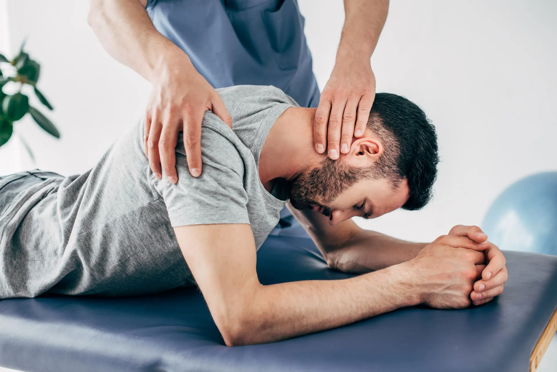 A man is laying on a table getting a massage from a doctor.