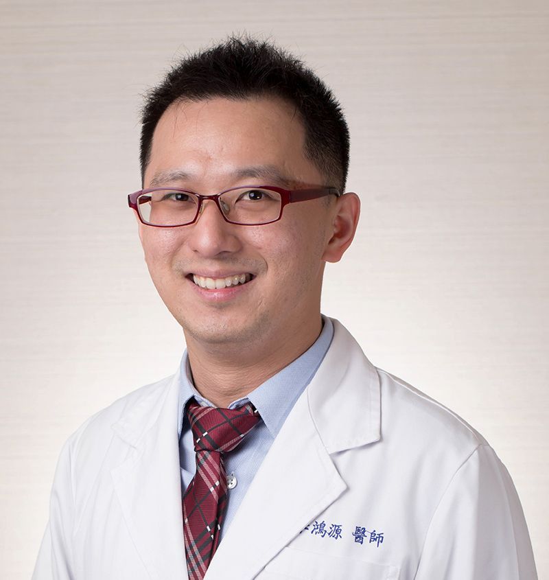 A man in a white coat and tie is smiling for the camera.
