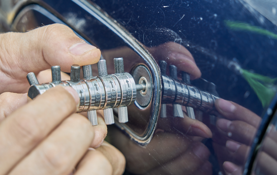 Person using a car lock pick on a blue car door.
