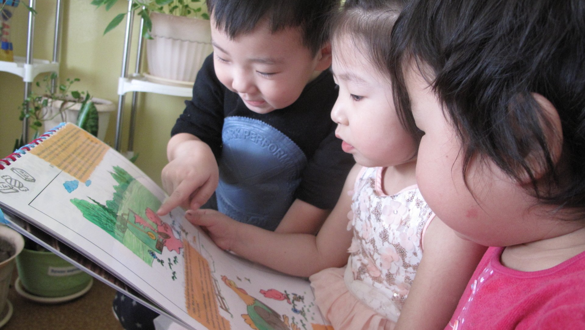 A group of children are reading a book together.