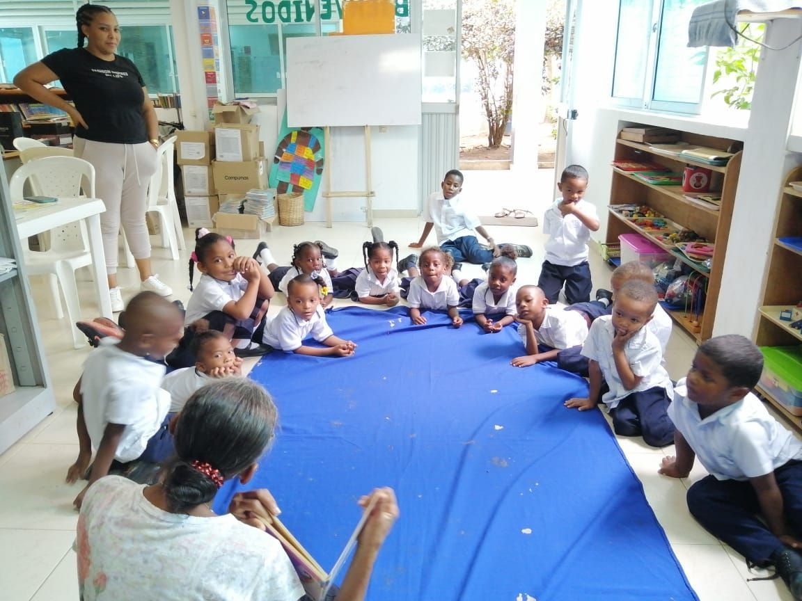 A group of children are sitting on a blue mat