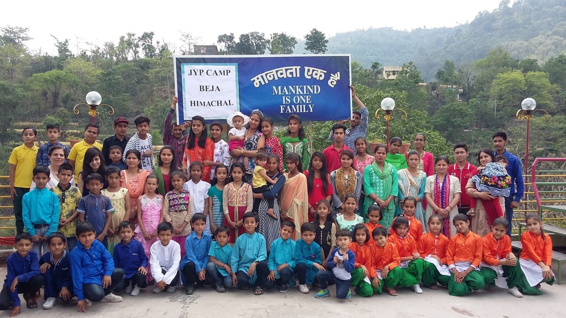 A large group of children are posing for a picture in front of a sign.