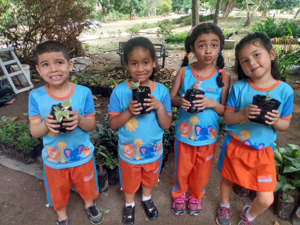 A group of children are holding potted plants in their hands