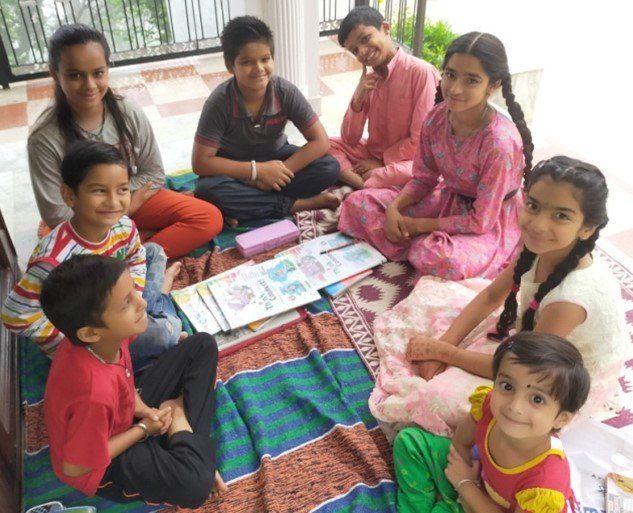 A group of children are sitting on a blanket on the floor.
