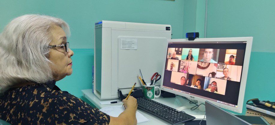 A woman is sitting in front of a computer monitor.