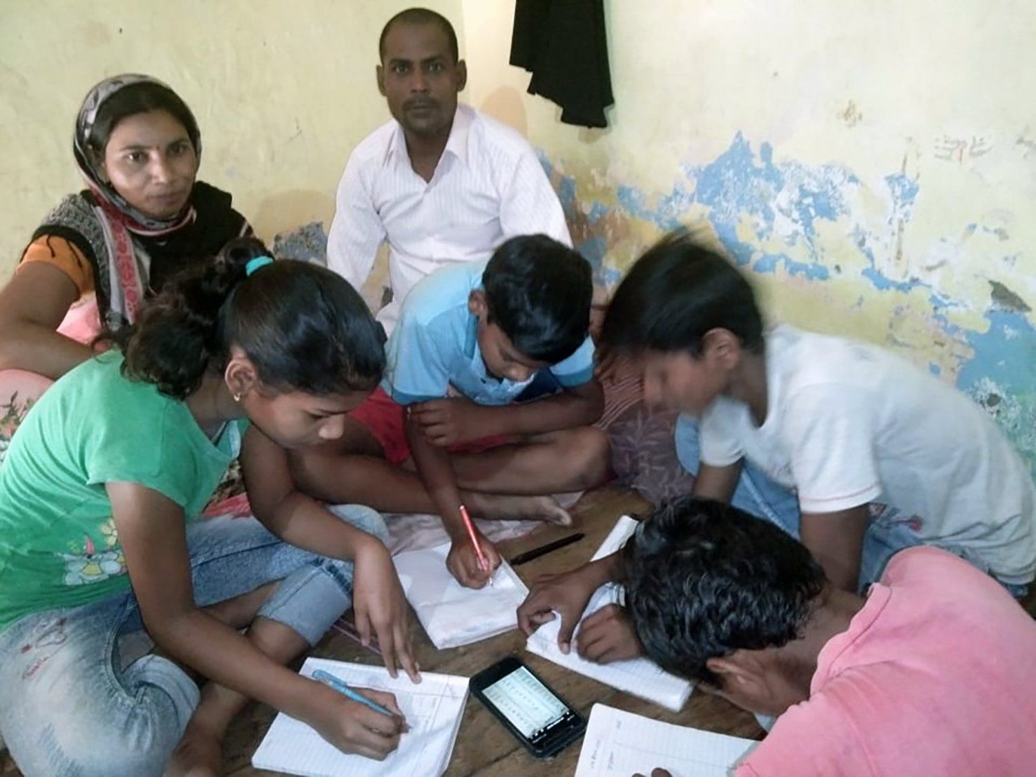 A group of people are sitting around a table writing in notebooks